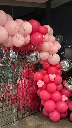 pink and white balloons are hanging from the side of a wall in front of a mirror