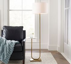 a living room with a black chair and a white rug in front of a window