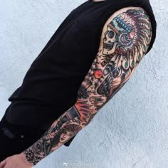 a man with a tattoo on his arm and shoulder is standing in front of a white wall