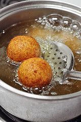 two fried food items are being cooked in a pot with boiling water on the stove