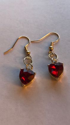 Shiny red glass rhinestone heart dangle earrings.  Metal Color: Gold Length: 3/8" Width: 3/8" Thickness: 1/4" Drop: 1 1/2" Trendy Red Dangle Heart Earrings, Elegant Red Metal Heart Earrings, Red Dangle Heart Earrings, Red Dangle Earrings With Heart Charm, Red Heart-shaped Earrings For Her, Heart Dangle Earrings, Rhinestone Heart, Red Earrings, Red Rhinestone