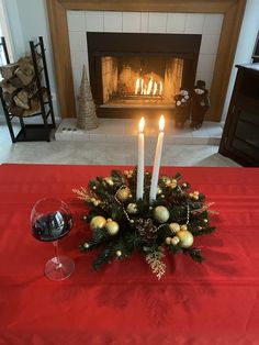 a christmas centerpiece with candles and ornaments on a table in front of a fire place