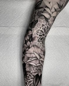 a black and white tattoo with flowers on the arm, done by an artist in his studio