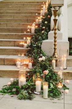 candles are lined up on the steps with greenery