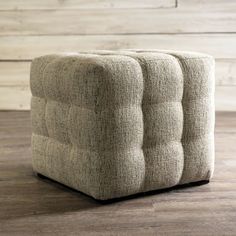 a square ottoman sitting on top of a wooden floor