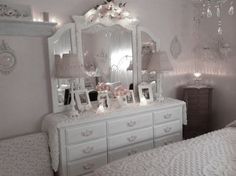 a white dresser sitting next to a bed in a bedroom under a chandelier