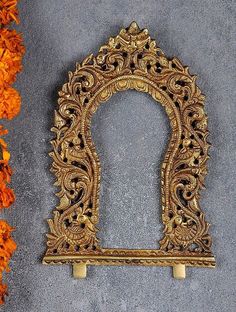 an ornate gold frame sitting next to orange flowers