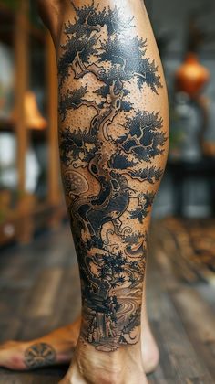 a man's leg with tattoos on it and an image of a tree in the background