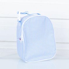 a blue and white gingham bag sitting on top of a table next to a wall