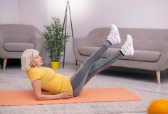 a woman is doing an exercise on a yoga mat in the living room with her legs spread out