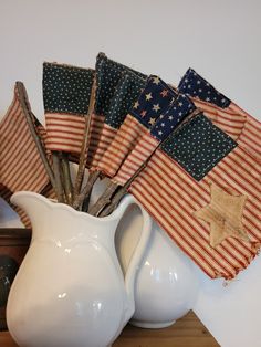 a white pitcher filled with american flags on top of a table