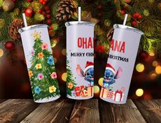 two tumblers with christmas designs on them sitting in front of a christmas tree