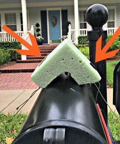 a green sponge on top of a black mailbox in front of a house