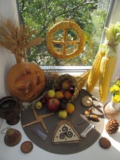 an assortment of fruits and vegetables on a table in front of a window with cornucopies