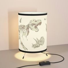 a lamp with a dinosaur print on it and a cord plugged into the light