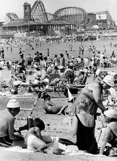 an old black and white photo of people on the beach in front of roller coasters