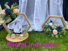 two hexagonal mirrors with flowers and candles in them on the grass next to each other