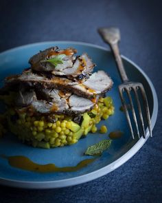 a blue plate topped with corn and meat next to a fork on top of a table