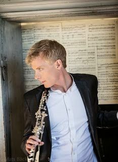 a man wearing a suit and tie holding a saxophone in front of an open book