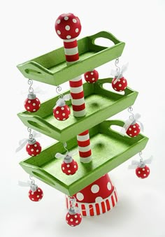 a green christmas tree with red and white ornaments hanging from it's bottom tier