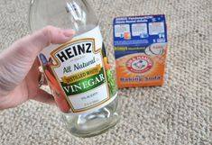 a hand holding a bottle of vinegar next to an empty carton of vitamins