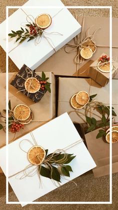 four wrapped presents with orange slices and greenery tied to them, sitting next to each other