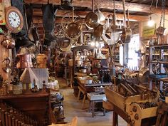 a room filled with lots of hanging pots and pans next to a clock on the wall