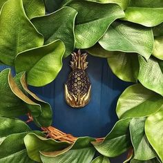 a close up of a wreath with leaves and a pineapple on it's front door