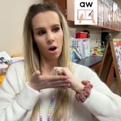 a woman with long blonde hair holding her hands out in front of her face and looking surprised