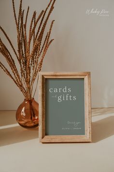 there is a sign that says cards and gifts next to a vase with dry grass in it