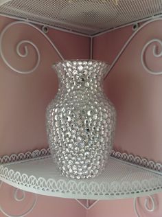 a glass vase sitting on top of a shelf in a room with pink walls and white shelves