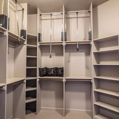 an empty walk - in closet with white shelving