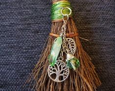 a green and silver keychain with a tree charm hanging from it's side