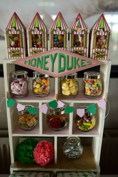 there is a shelf that has some candy in jars on it and the words honey dukes above it