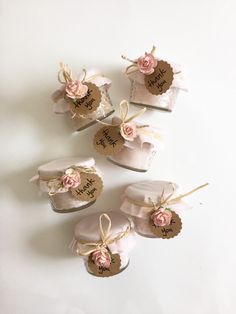 four small cakes with pink flowers on them and tags attached to the top, sitting next to each other