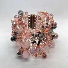 Pink, silver and grey beads have been generously interwoven with copper wire giving this bracelet a luscious look and feel. The beads are a mix of glass, stone and pearls and many have been recycled from preloved jewellery. Sure to attract many complements, this bracelet can be custom made to your size.  MEASUREMENTS:  The length of the bracelet will depend on your wrist measurement. Please message me with the measurement of the circumference of your wrist and I will make the bracelet a bit bigg Elegant Pink Metal Crystal Bracelet, Elegant Metal Beaded Bracelets With Natural Stones, Pink Metal Jewelry With Colorful Beads, Wire Wrapped Rose Gold Bracelet, Rose Gold Wire Wrapped Bracelet, Handmade Metal Beaded Bangle Bracelets, Handmade Metal Beaded Bangle Bracelet, Elegant Metal Bracelets With Colorful Beads, Handmade Metal Bangle Beaded Bracelets