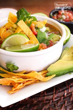 a white plate topped with a bowl of soup and tortilla chips