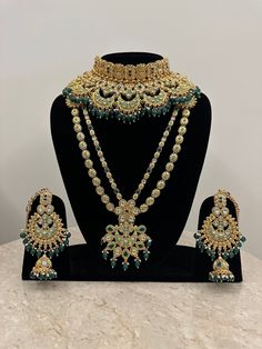 Full bridal set in hues of green for the beautiful bride! This glamorous bridal kundan necklace set features shimmering faux kundan stones intricately handcrafted in meenakari and decorated with green beads. The set comprises of 9 pcs including a long necklace, a princess necklace, pair of beautiful earrings with kaan chains, a mathapatti, a nose rings bajubandh and a pair of haathphool. Dimensions: Long Necklace Length-16 Inches Princess Necklace Width-3.75 Inches Earrings Length-4.75 Inches Earrings Width-2.75 Inches Kaanchain Length-5.25 Inches Weight of Each Earring-68 gms Matha Patti Tika Drop-5.25 Inches Nosering Dia-1.75 Inches All products are manufactured using traditional skills from our rich heritage of crafts.  The process of these crafts is essentially manual. Hence, any irreg Indian Bridal Jewelry, Kundan Necklace Set, Indian Bridal Jewelry Sets, Necklace Set Indian, Princess Necklace, Bridal Jewelry Set, Kundan Necklace, Bollywood Jewelry, Bridal Jewellery Indian