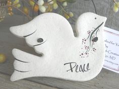 a white bird ornament sitting on top of a wooden table next to flowers