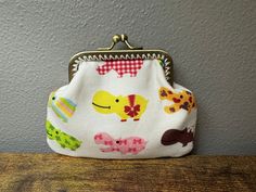 a small purse sitting on top of a wooden table next to a gray wall with an elephant and giraffe pattern