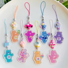 six different colored teddy bear key chains on a white plate