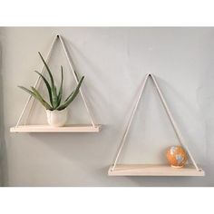 two white shelves with plants and an orange ball on them, hanging from the wall