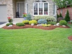 a house with landscaping in front of it and grass around the yard, including shrubs