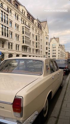 an old car is parked on the side of the road in front of some buildings