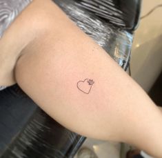 a small heart tattoo on the back of a woman's left arm, with a dog paw in it