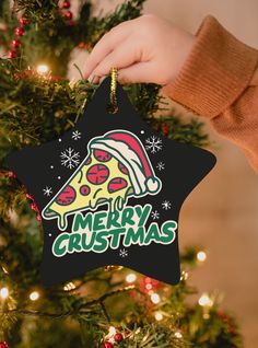 a person holding a christmas ornament in front of a tree