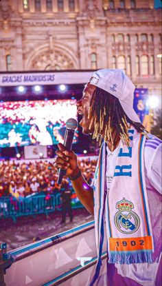 a man with dreadlocks holding a microphone in front of an audience at a concert