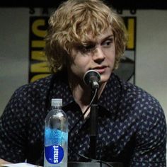 a young man sitting in front of a microphone