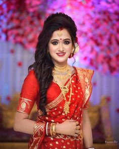 a woman in a red and gold sari posing for the camera with her hands on her hips