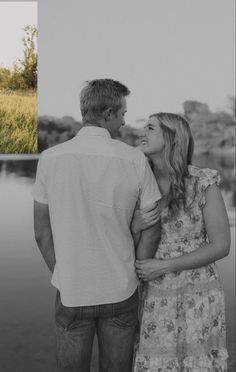 a man and woman standing next to each other in front of a body of water